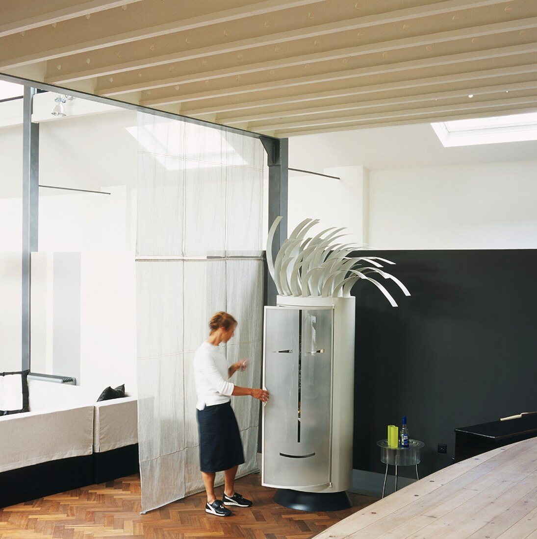 Loft-style interior - whimsical cylindrical cupboard with punk hairstyle and stylised face on door being opened by woman