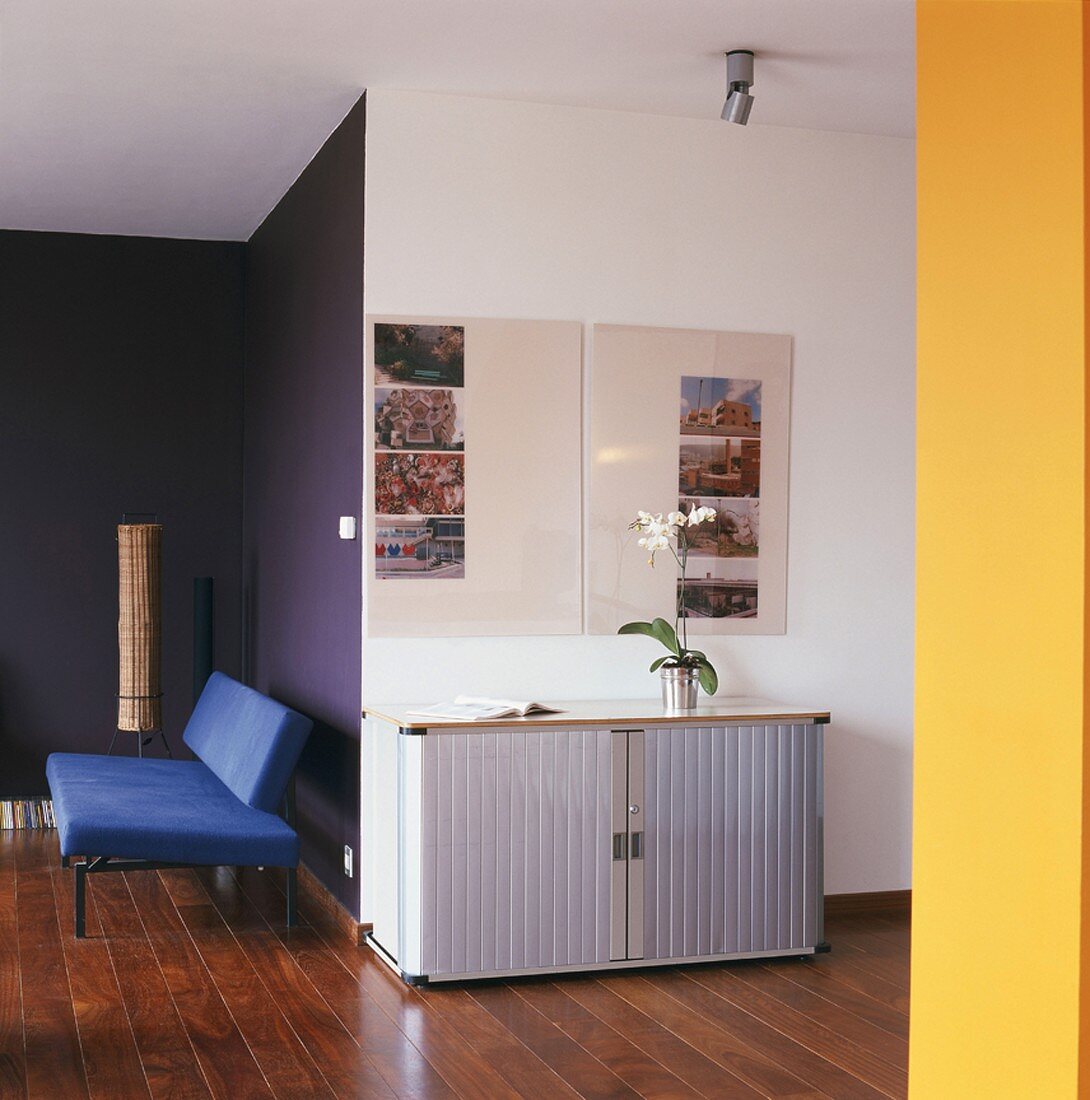 Wohnraumausschnitt mit blauem Sofa und Sideboard mit Rolltür