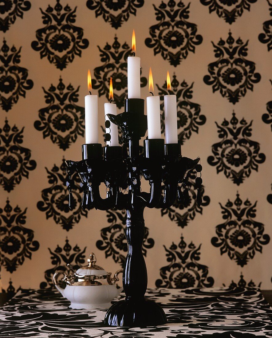 A black candle holder against black and white wallpaper