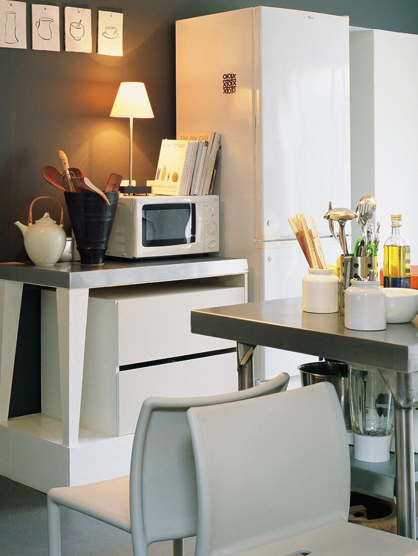 Ausschnitt einer Küchenzeile mit Stehlampe auf dem Mikrowellenherd und Kunststoffstühlen