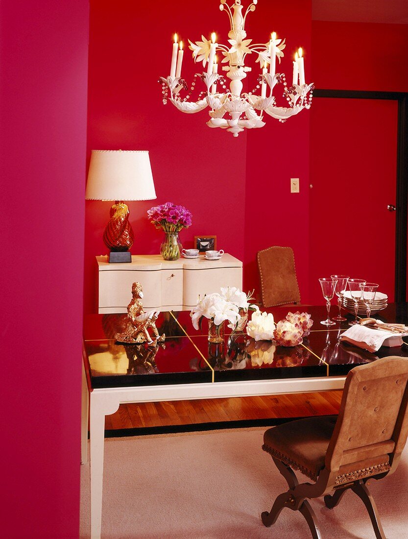 Feminines Esszimmer mit verspieltem Kronleuchter und Stilmöbeln umgeben von magentafarbenen Wänden