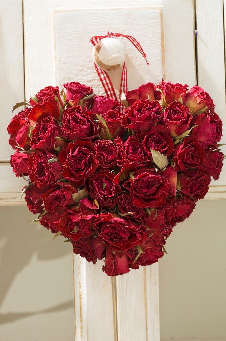 Herz aus getrockneten roten Rosenblüten an Türknauf