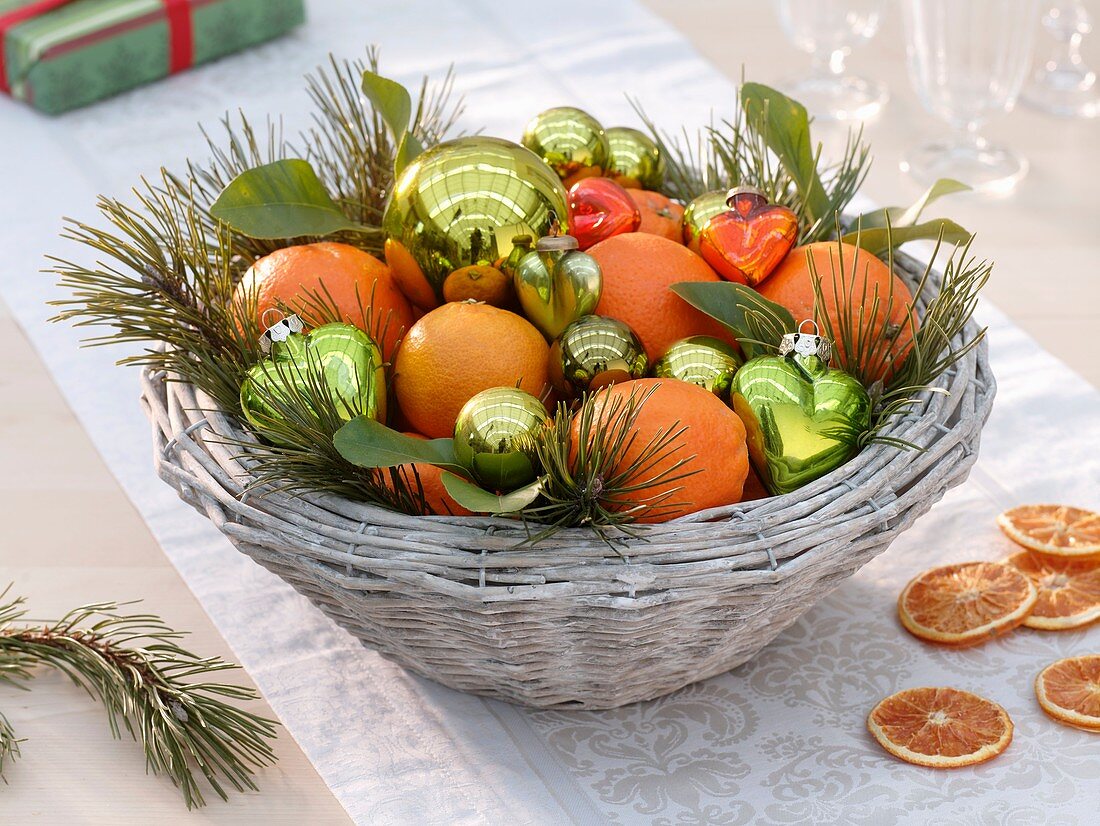Basket of oranges, pine sprigs and baubles (Christmas)