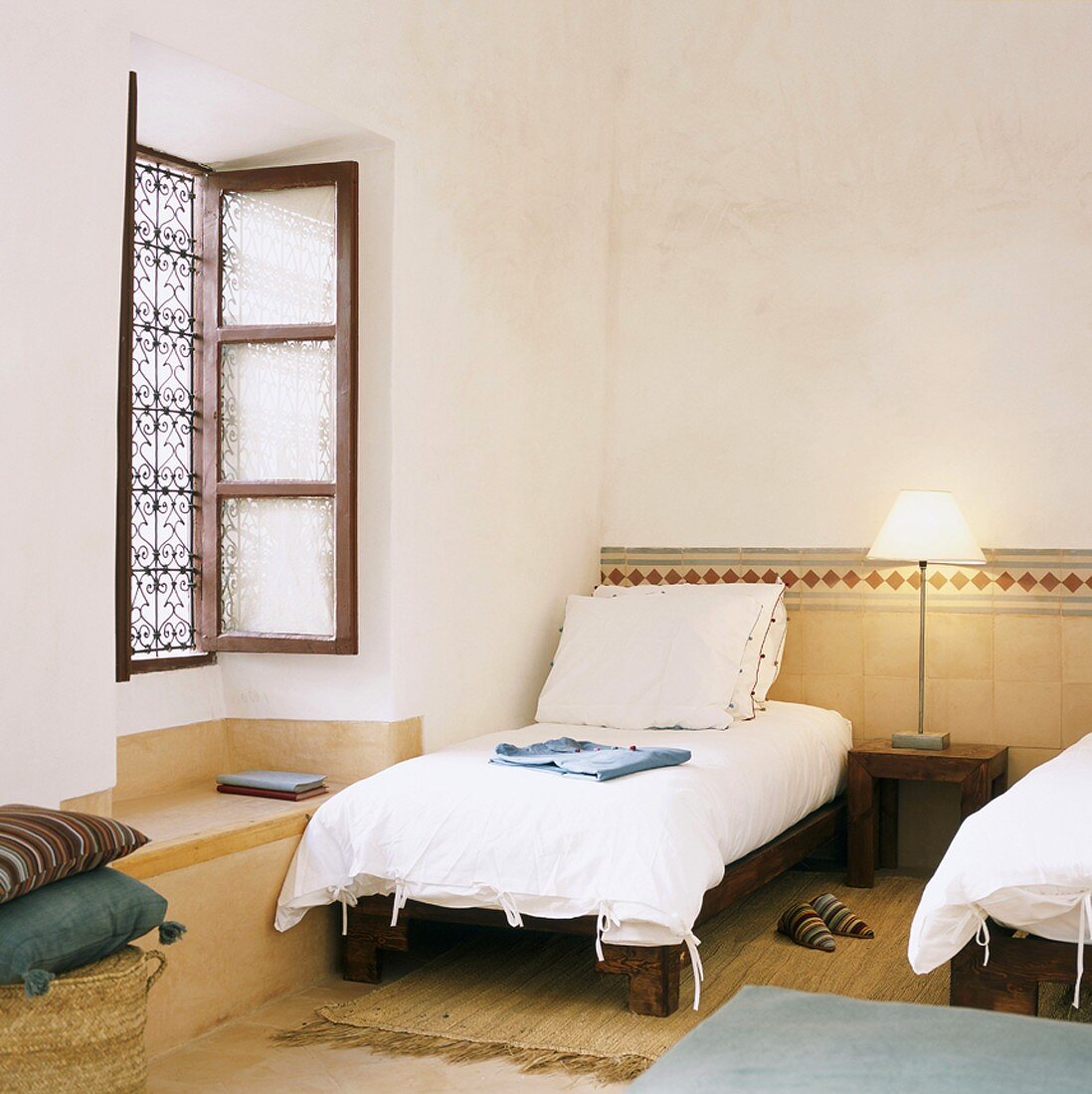 Simple, Oriental-style bedroom with half-height tiled wall and wrought iron window grille