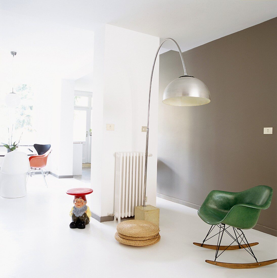 Offener Wohnraum im Loftstil mit grünem 50er Jahre Schaukelsessel, 70er Jahre Bogenlampe und Zwergen-Beistelltisch