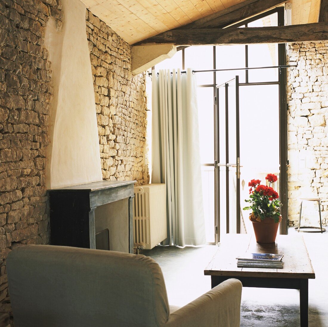 Rustikaler Wohnraum mit Natursteinwänden, Holzdecke und Glasfront