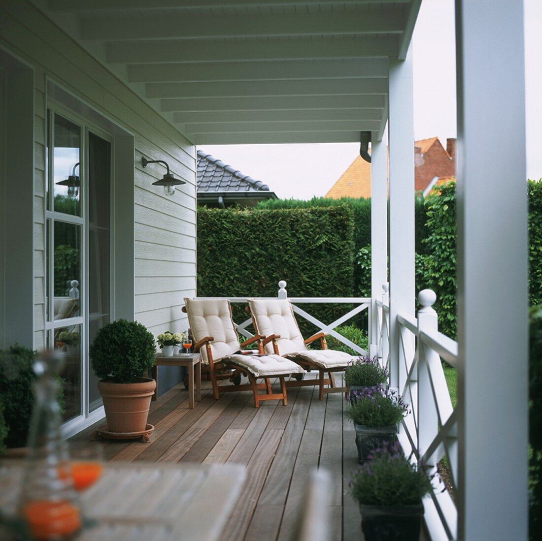 Terrace with wooden boards, planters and upholstered loungers