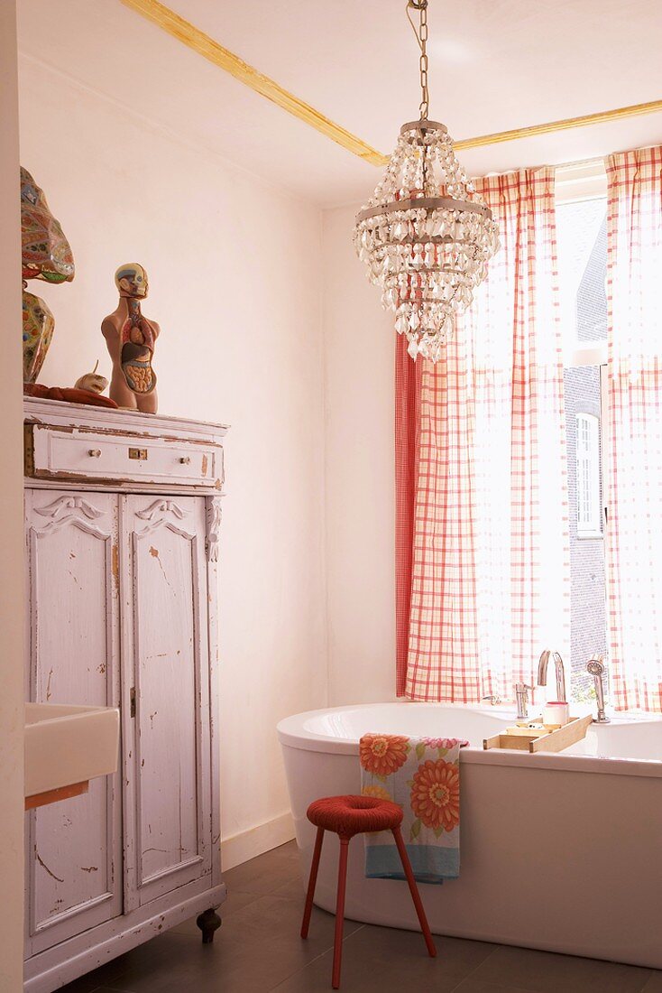 Badezimmer mit Vintage-Schrank, Kristallleuchter und freistehender Badewanne