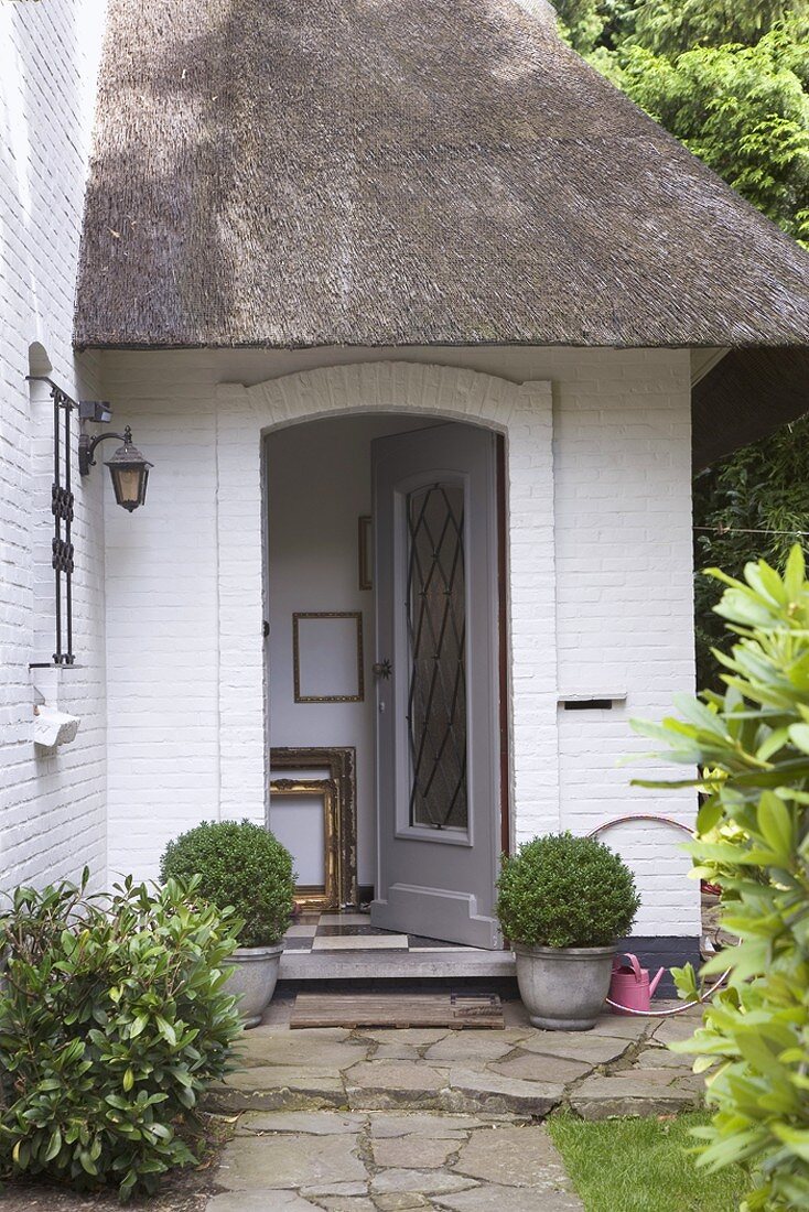 Open front door of brick house with thatched roof