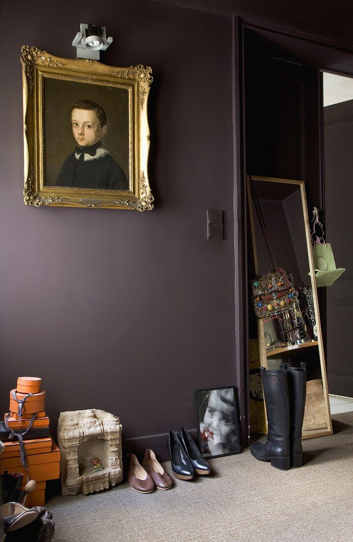 Shoes below gilt-framed portrait of child on grey-brown wall