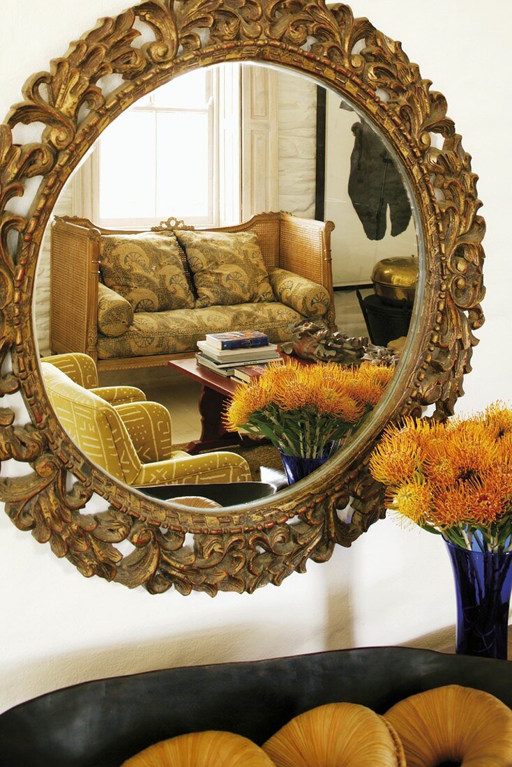 Living room reflected in round mirror with carved wooden frame