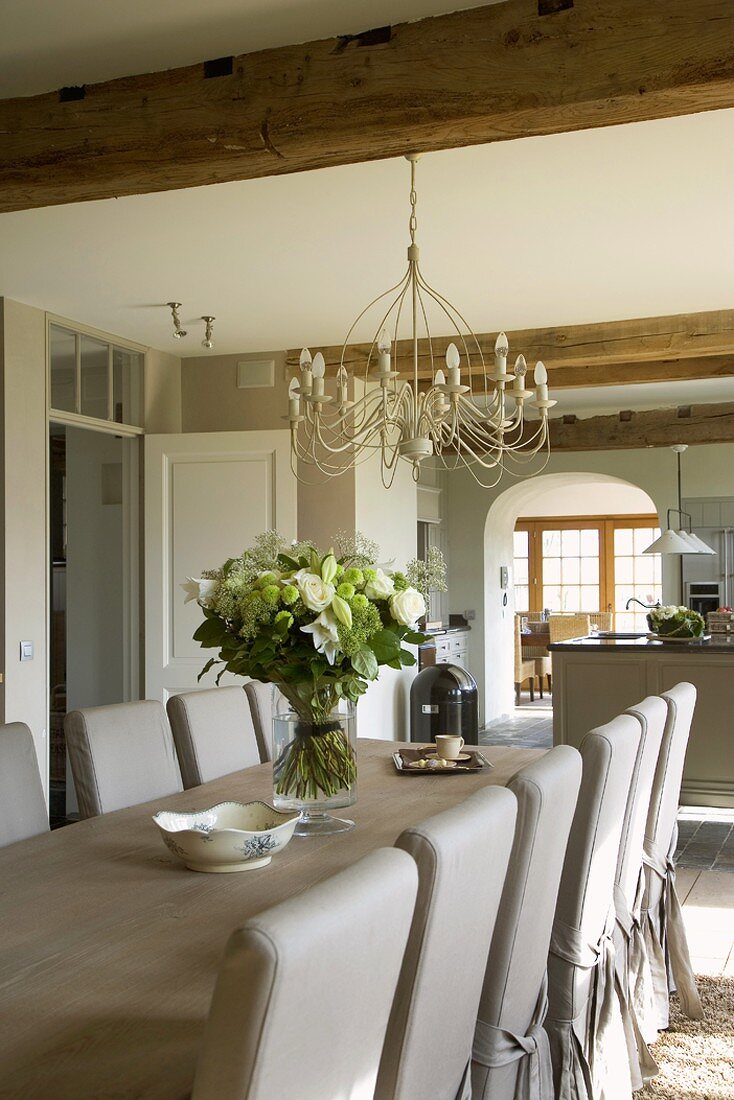 Long dining table, loose-covered chairs and magnificent bouquet of summer flowers