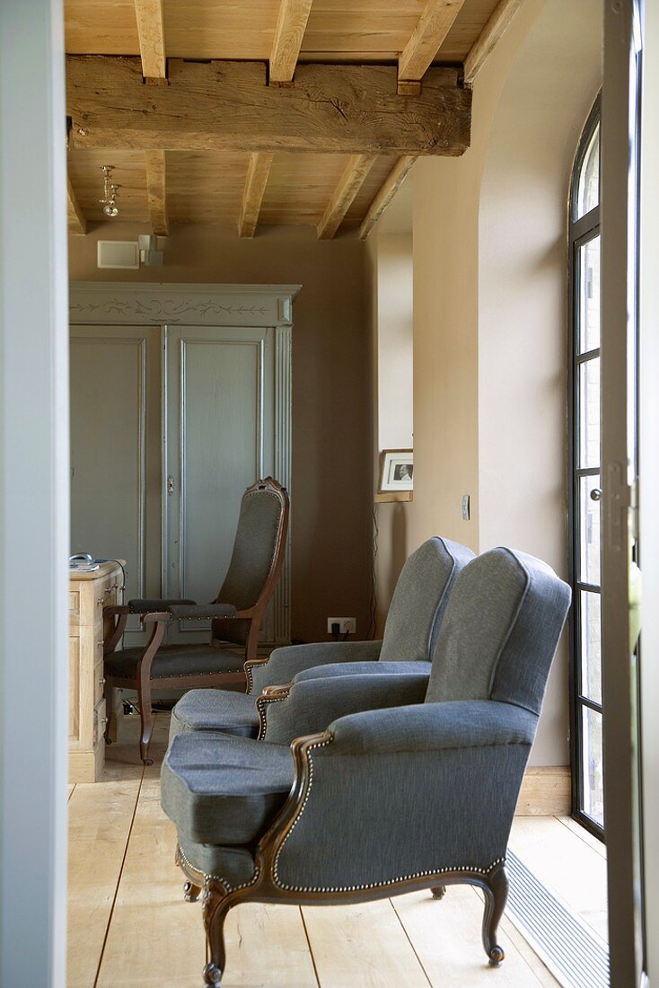 Antique blue armchairs in front of French windows
