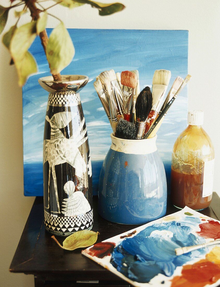 Painting utensils and vase on side table