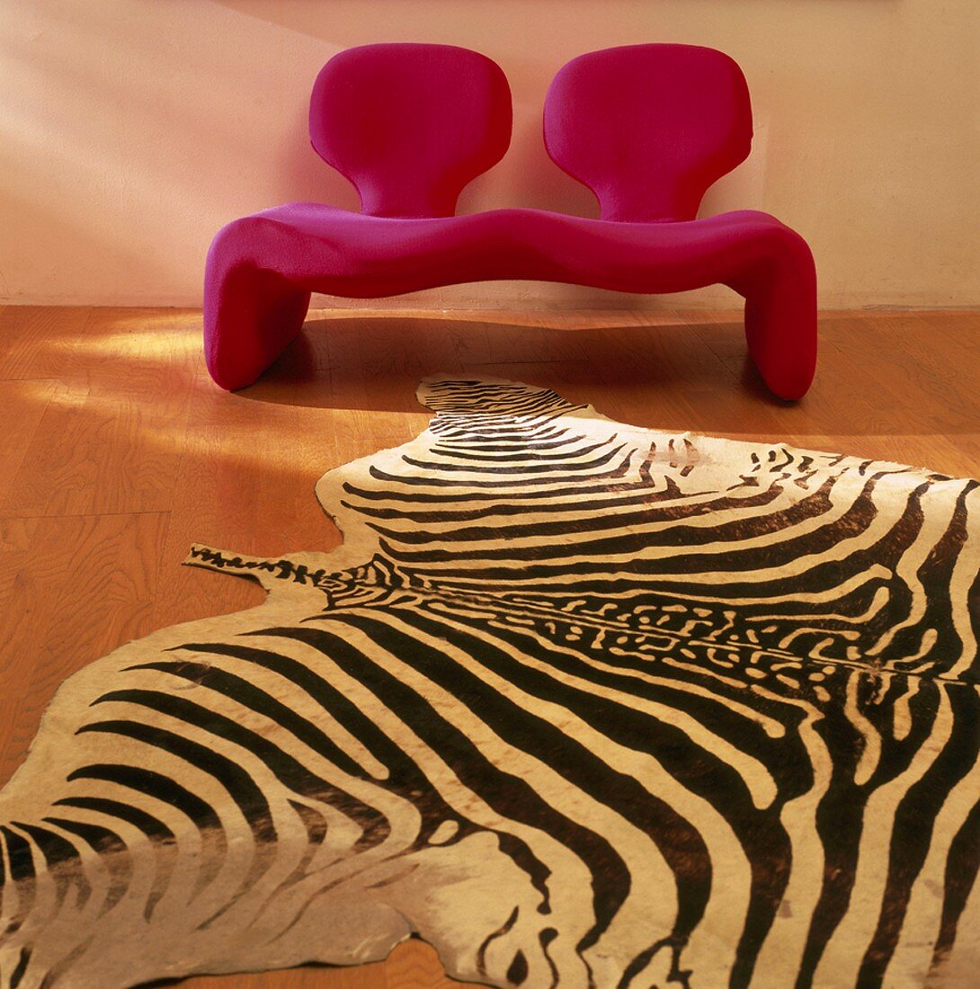 Eine rote Couch mit Lehnen und Zebra-Teppich