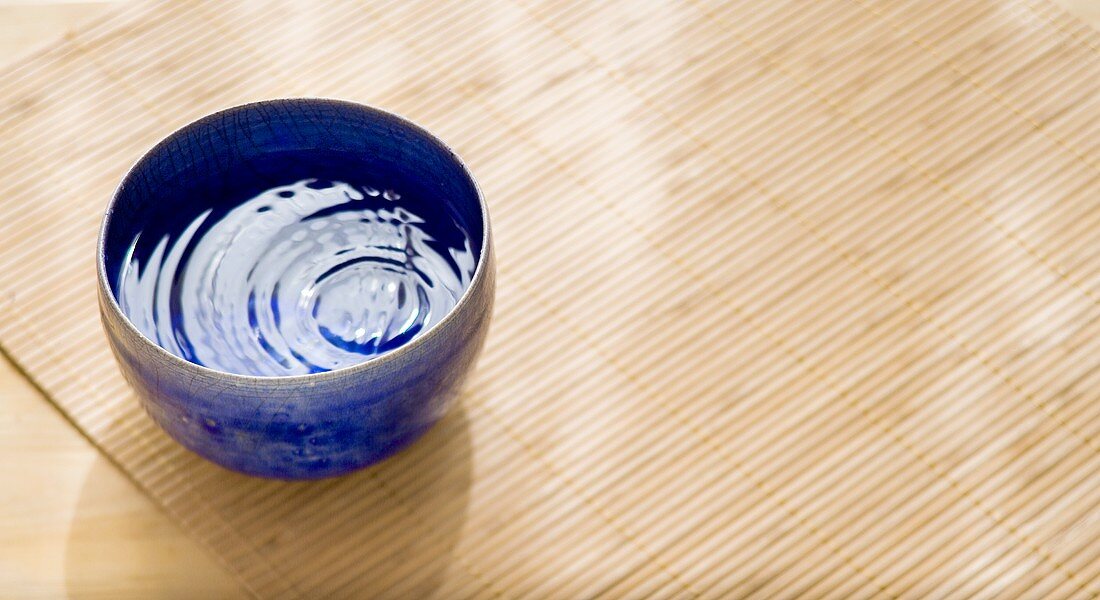 Bowl of water on bamboo mat