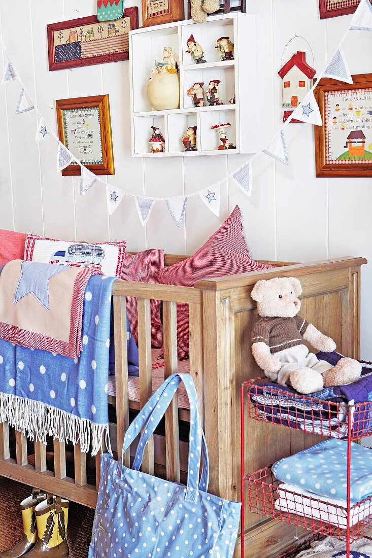 Kinderzimmer mit Gitterbett aus Holz, Decken, Kissen & Wimpelkette