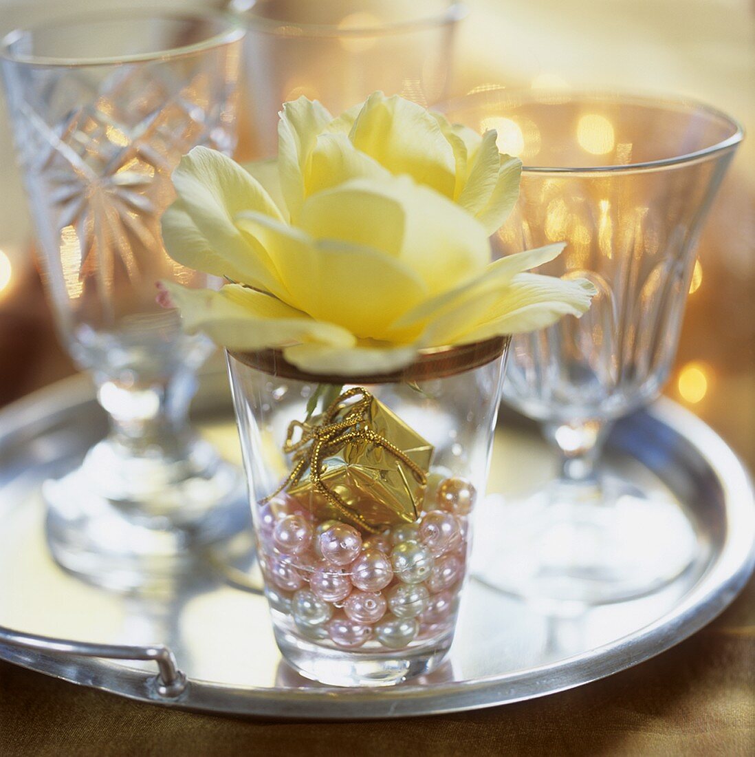 Festive decoration: tiny parcel, beads & yellow rose in glass