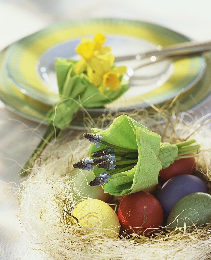 Osternest mit gefärbten Eiern und Blumensträusschen