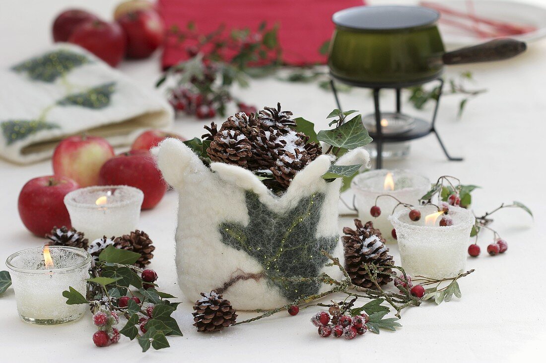 Wintry table decoration of candles, cones, crab apples & felt