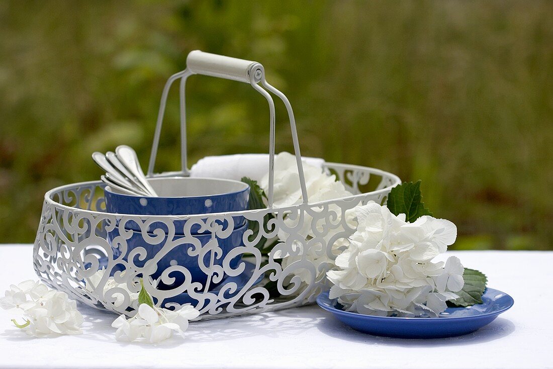 Tableware in basket, white hydrangeas