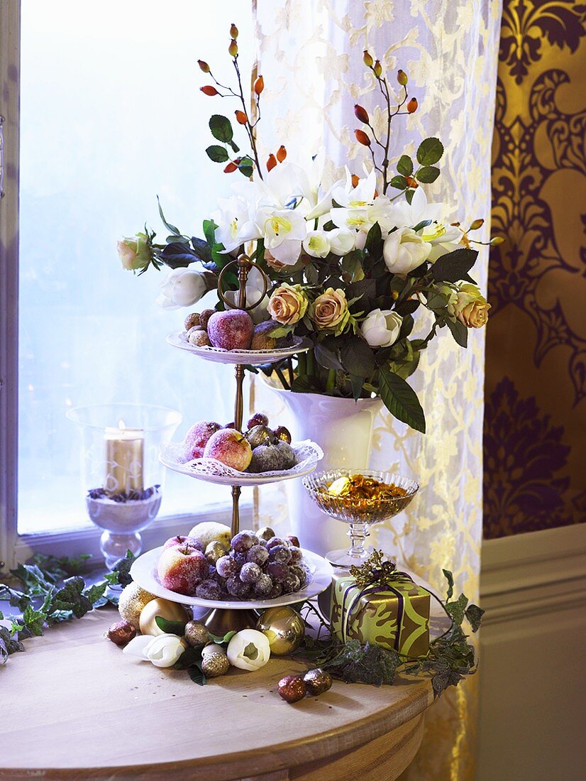 Sugared fruit on tiered stand and flowers by window