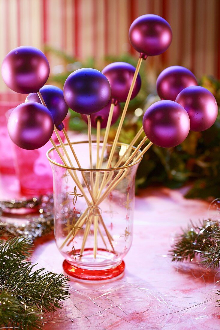 Purple Christmas baubles on sticks in glass