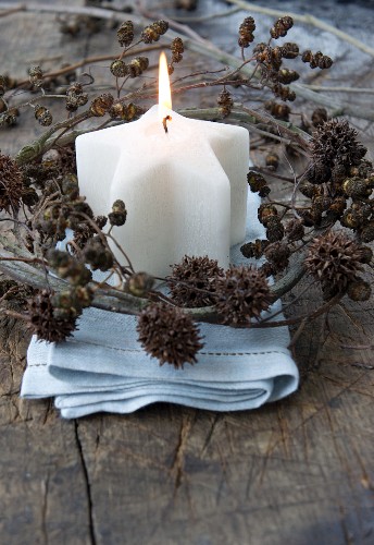 A star-shaped candle with a wreath of alderberry and maple fruit sprigs