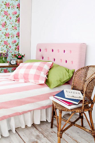 Bed with pink, button-tufted, DIY headboard in feminine bedroom