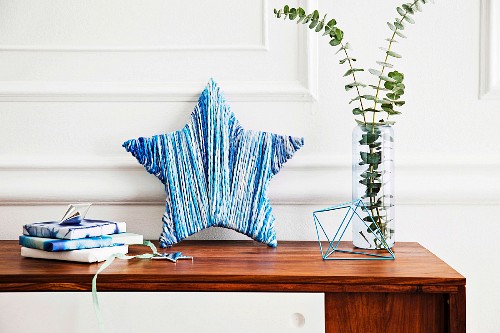 DIY decorative stars wrapped in wool in shades of blue and arranged decoratively with a glass vase and gifts