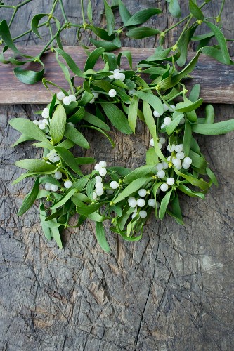 Wreath of mistletoe and berries on a rustic wooden table