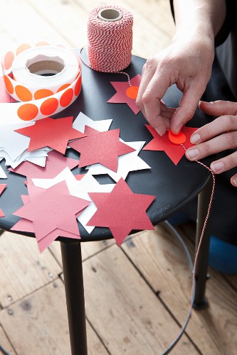 Hands sticking red dot on cut-out paper stars