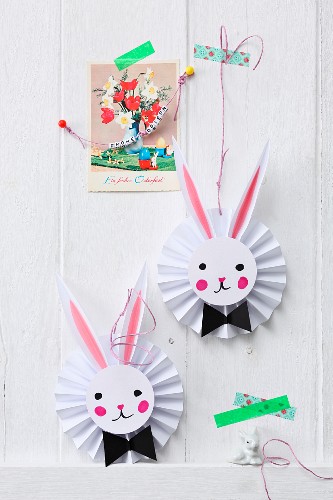 Vintage greetings card and Easter bunnies on paper rosettes decorating wall