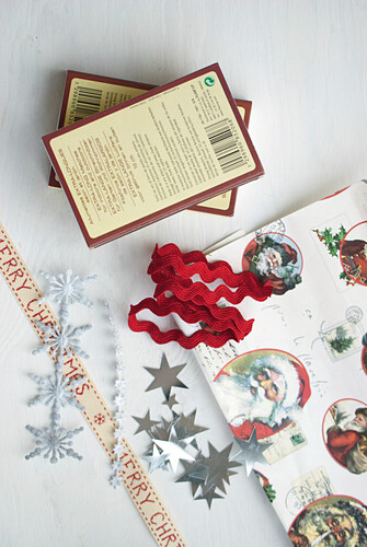 Christmas wrapping paper with vintage Father-Christmas pattern next to matchboxes, ribbons and silver stars