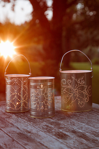 Candle lanterns made from recycled tin cans with perforated patterns