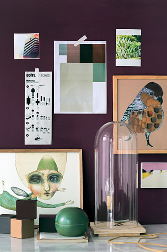 Handmade lamp under glass cover in front of pictures on purple wall