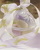 Easter eggs in egg-shaped bowl with gift ribbon
