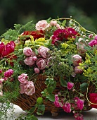 Basket of roses in various shades of red with asparagus fern