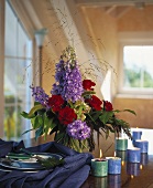 Table with candles and bouquet of delphiniums and roses