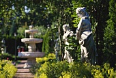 Blick in einen Garten mit Steinbrunnen und Steinfiguren