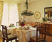 Chandelier above table laid for afternoon coffee with summer bouquet in traditional interior