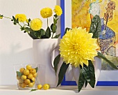 Yellow dahlias in vases and yellow plums in glass