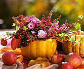 Chrysanthemums, rose hips, heather & serviceberries in pumpkin