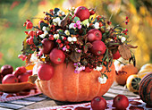 Hollowed-out pumpkin with apples, snowberries & spindle berries
