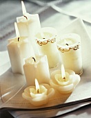 Various white candles burning on white napkins