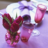 Red tulips in small vase beside place-setting