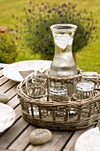 A carafe of water and glass on a tray on a garden table