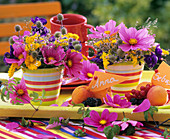 Bunte Blumengestecke und Früchteteller mit Kärtchen