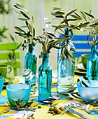 Olivenzweige in Flaschen als Tischdeko