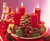 Adventskranz aus Zapfen und Moos mit roten Kerzen